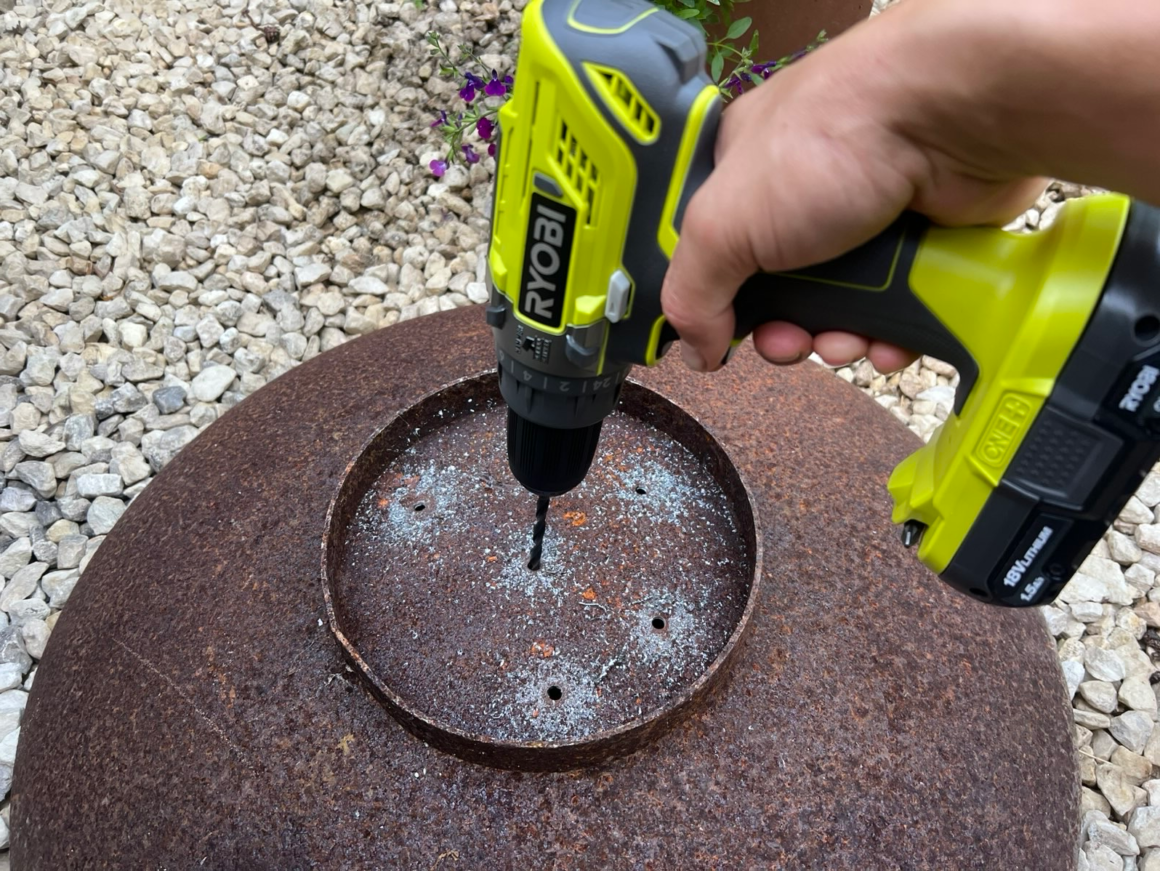 Electric power drill making holes in the bottom of a corten steel bowl